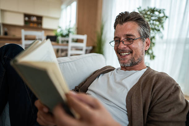 istock Mature man relaxing at home reading book and smiling 2240987691