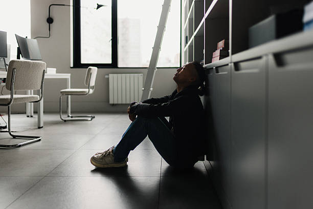Exhausted office worker resting on the floor by cabinets after a long day in a modern workspace