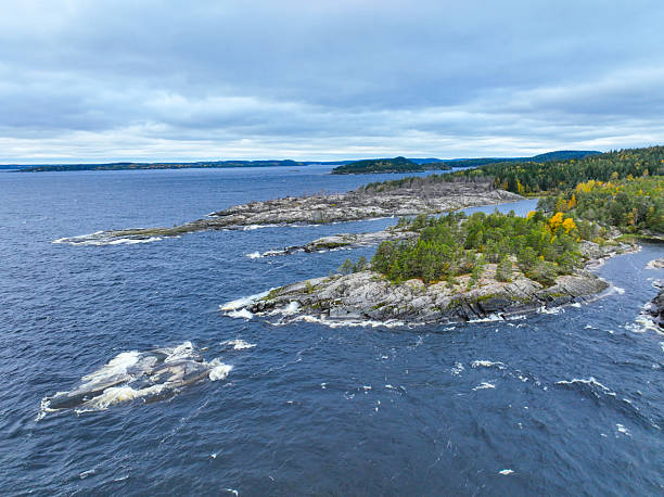 istock Small rocky island surrounded by rough open water and forest 2240990416