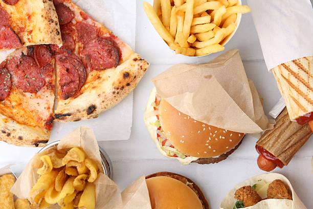 Different delicious fast food on white tiled table, flat lay