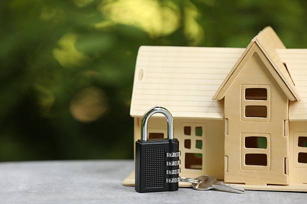 istock Home security. House model, key and padlock on light grey table outdoors, closeup. Space for text 2240990783