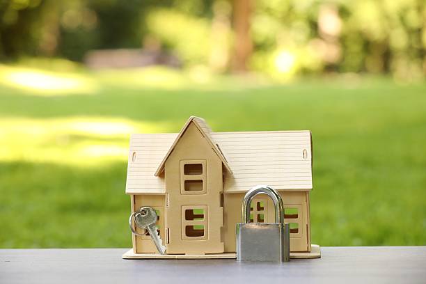 istock Home security. House model, key and padlock on light table outdoors, closeup 2240991093