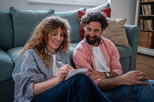 istock Happy couple writing notes together on living room floor 2240992865