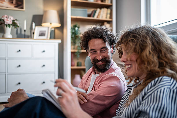 istock Happy couple relaxing at home solving crossword puzzle 2240992899