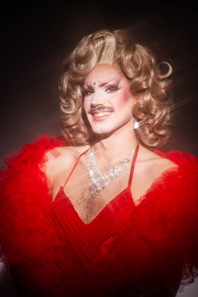 istock Glamorous Drag Queen Smiles in Vibrant Red Attire Against a Studio Backdrop 2240994821