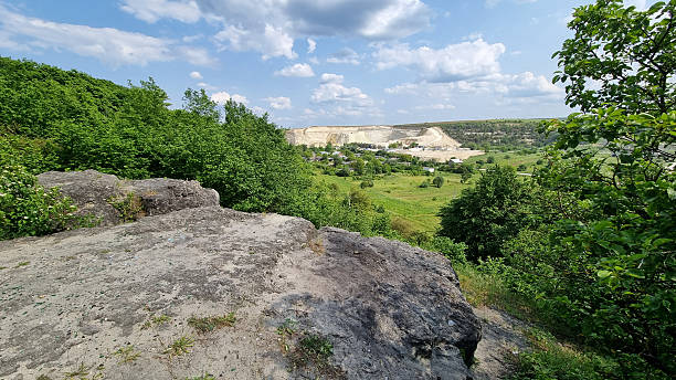 Rocky viewpoint overlooking a quarry and green valley with cloudy sky