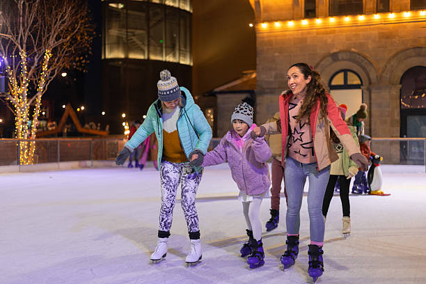 Family of women and children ice skating at Christmas in Newcastle upon Tyne at night. They are dressed warmly with coats and wooly hats on.Videos are available similar to this scenario.