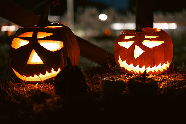 istock Carved glowing Halloween pumpkins with candles in dark night. 2241003785