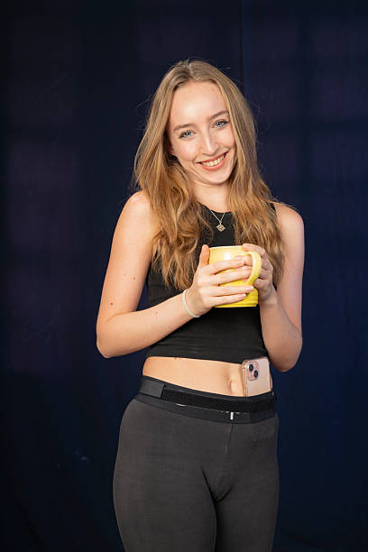 istock Joyful young woman with a yellow mug, radiating happiness while her smartphone is shown. 2241004276