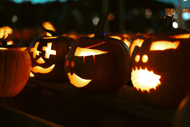 istock Carved glowing Halloween pumpkins with candles in dark night. 2241004308