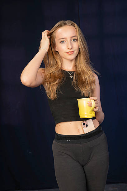 istock Young female holding a mug with a casual outfit against a dark backdrop. 2241004524