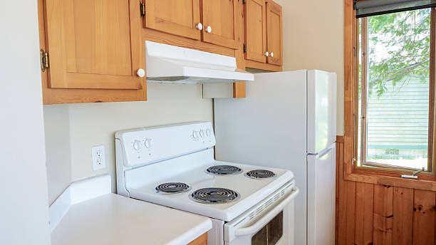 Bright kitchen space showcases white appliances and wooden cabinets, with sunlight filtering through the window, enhancing the inviting ambiance