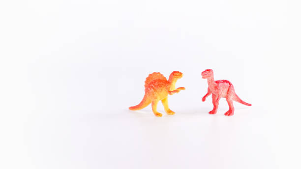 little girl showing her teeth to a t-rex puppet that has its mouth open on white background