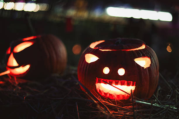istock Carved glowing Halloween pumpkins with candles in dark night. 2241005242