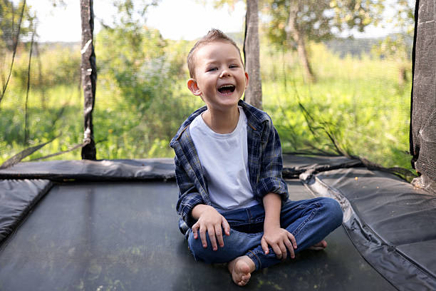 istock Happy boy sitting on black trampoline outdoors 2241020923