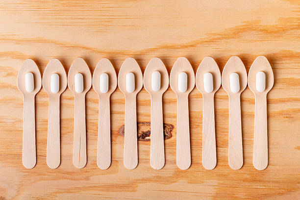 istock White tablets in wooden spoon from above on a wooden desk. 2241023716