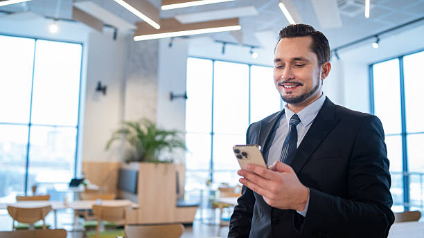istock Smiling professional checking phone in bright office, representing connectivity and joy. 2241024198