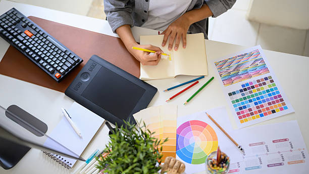 istock Top view creative woman sketching logo ideas in notebook with color samples and pencils 2241024645