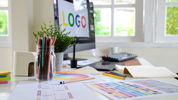 istock Creative woman designing logo sketches on notebook with color samples and tools in bright modern workspace 2241024665