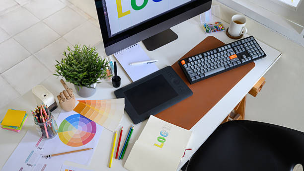 istock Creative woman designing logo sketches on notebook with color samples and tools in bright modern workspace 2241024671