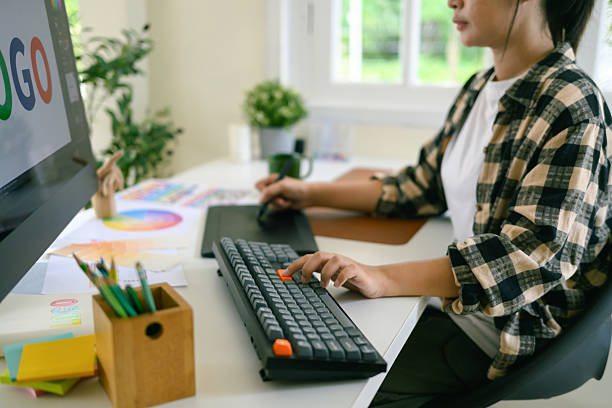 Closeup graphic designer working on computer with color palette and tablet in bright modern creative workspace