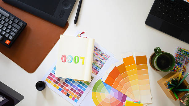 istock Top view of creative workspace with color palette, digital tablet, and notebook sketching logo design on clean white desk 2241024775