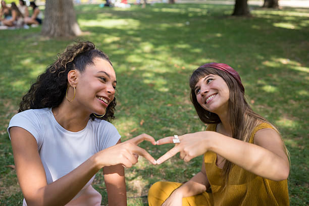 istock Young women friends forming heart shape with hands 2241032748