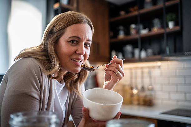 istock Woman eating healthy breakfast cereal in kitchen 2241032966