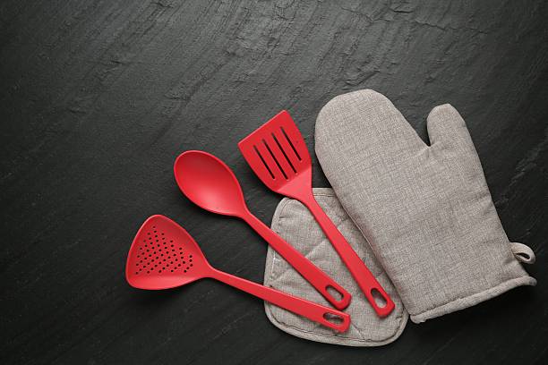istock Grey oven glove and other kitchen utensils on dark textured table, flat lay 2241033192