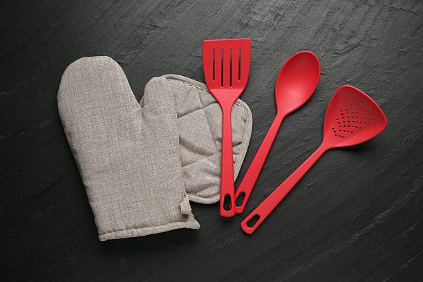 istock Grey oven glove and other kitchen utensils on dark textured table, flat lay 2241033332