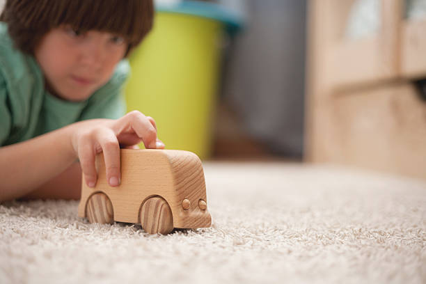 istock Boy playing with wooden van on floor in soft focus 2241035116