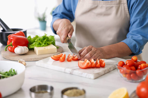 istock Senior woman cooking at white marble table in kitchen, closeup 2241035639