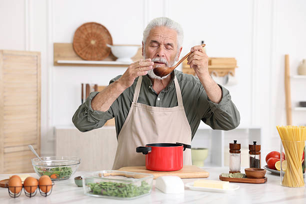 istock Elderly man cooking at white marble table in kitchen 2241035718