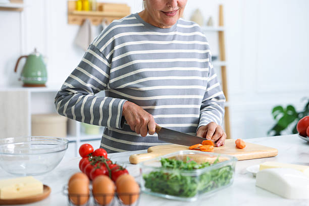 istock Senior woman cooking at white marble table in kitchen, closeup 2241035791