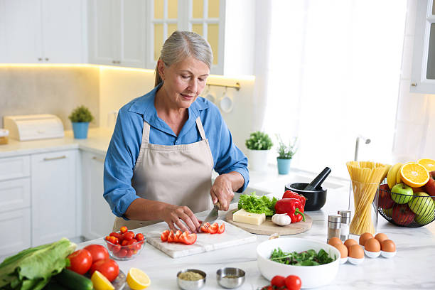 istock Senior woman cooking at white marble table in kitchen 2241035804