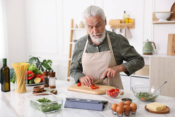 istock Elderly man cooking at white marble table in kitchen 2241036107