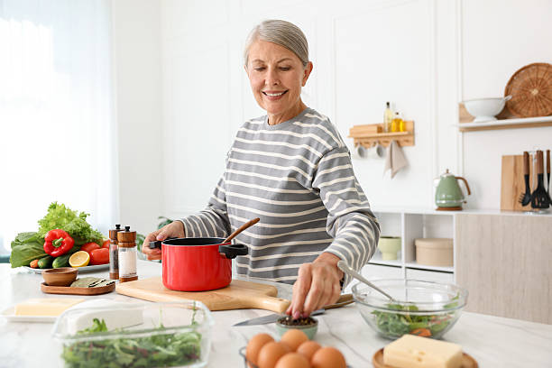 istock Senior woman cooking at white marble table in kitchen 2241036357