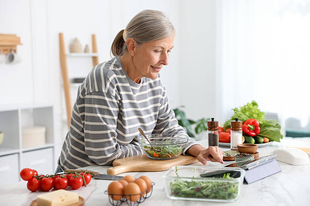 istock Senior woman using tablet while cooking at white marble table in kitchen 2241036500