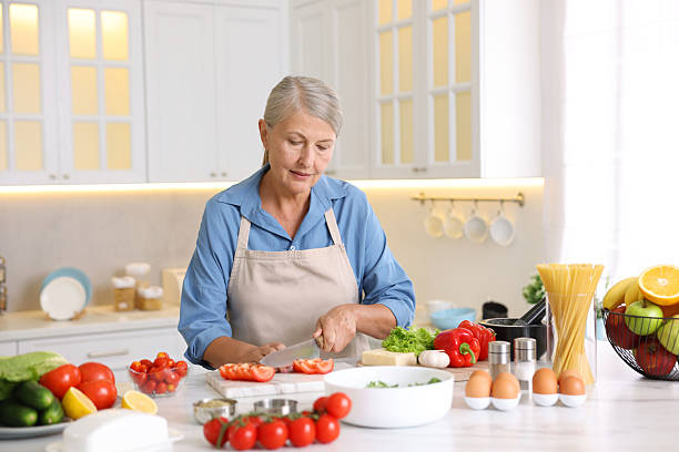 istock Senior woman cooking at white marble table in kitchen 2241036505