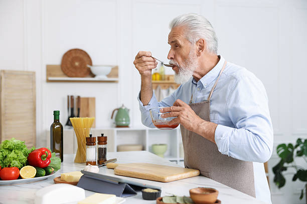 istock Elderly man cooking at white marble table in kitchen 2241036627
