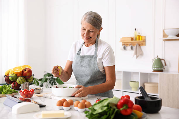 istock Senior woman cooking salad at white marble table in kitchen 2241036672