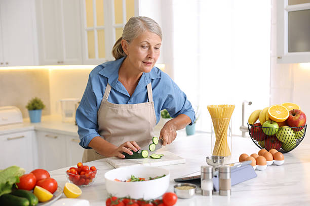 istock Senior woman using tablet while cooking at white marble table in kitchen 2241036829