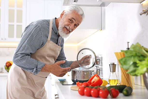 istock Elderly man cooking dish on cooktop in kitchen 2241036932