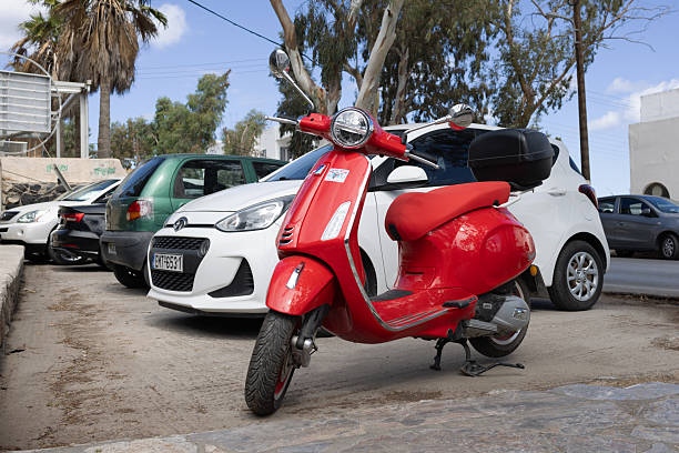 Valencia, Spain - August 10, 2025: Side view of red motor scooter parked next to bus stop in the city of Valencia, Spain. This is a very used alternative to cars to move quickly and efficiently all around the city
