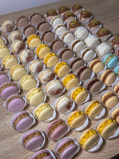 A vibrant assortment of gourmet French macarons and delicate mini desserts, showcasing a delightful array of colors and exquisite fillings, neatly arranged on a rustic wooden table, perfect for a