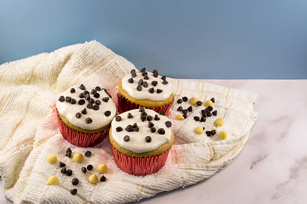 istock Three Vanilla Cupcakes With White Frosting And Chocolate Chips On Cool Blue And Marble Backdrop 2241043242