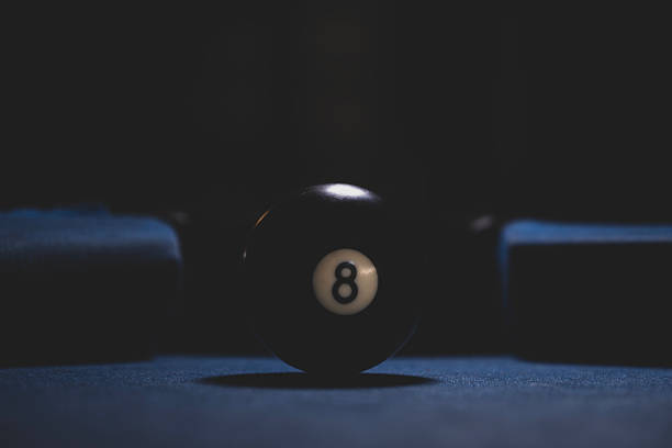 Close-Up of eight ball on blue pool table. Billiard eight ball ready for the final shot. Black eight ball on a billiard table. Focused eight ball in billiards game.
