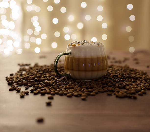 istock a cozy coffee setting with a richly layered cappuccino surrounded by scattered coffee beans, set against a warm backdrop of soft bokeh lights evoking a festive, intimate atmosphere, layers, elegant 2241043903