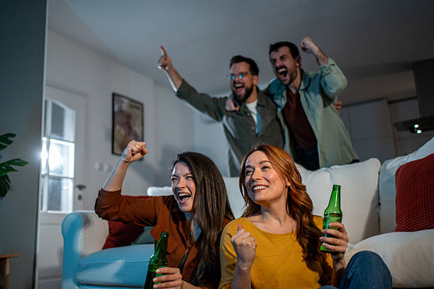 istock Friends cheering and celebrating while watching sports at home 2241044117