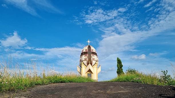 Unique egg-shaped chapel on a green hill under clear blue sky, religious landmark in rural landscape